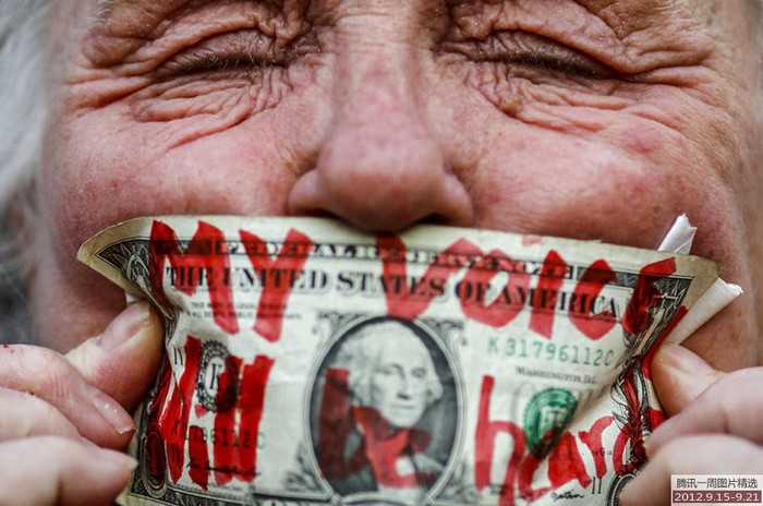 Một cụ già dùng tờ tiền bịt miệng nhân kỉ niệm 1 năm ngày nổ ra phong trào "Chiếm Phố Wall" ở Mỹ